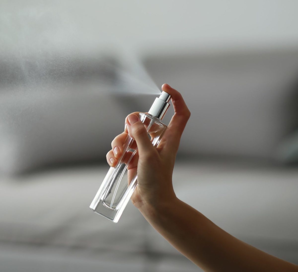 Woman spraying air freshener indoors closeup. Space for text